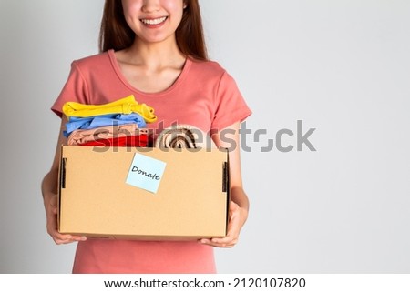 Woman holding donate box with clothes over white background.