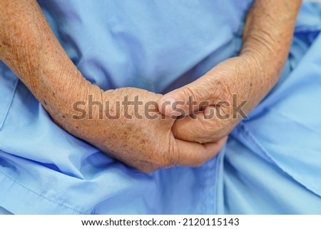 Asian elder senior woman patient put holding hands on her
lap alone for waiting her family.                             
