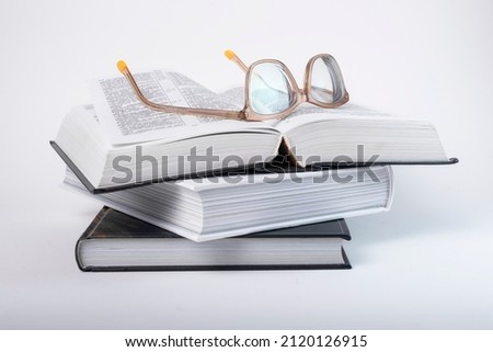 Glasses at books stack. Education, preparing for exams, information search concept. Books, codes or novels on grey background. High quality photo