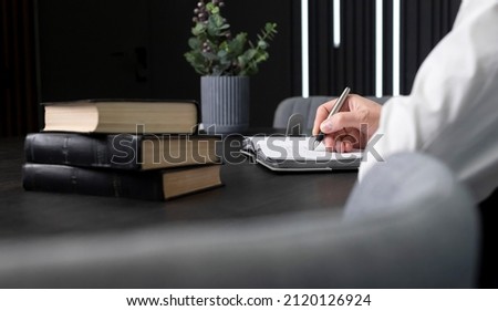 Man hands taking notes in notebook. Businessman sitting at table with books or codes and writing agenda, information for education or work. High quality photo