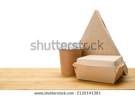 Lunch food delivery concept. Set of paper containers (pizza, hamburger, coffee paper cup) on a wooden table. Isolated background.