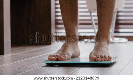 Close-up male legs slender thin sporty unrecognizable guy male athlete standing at home bathroom walking barefoot on electronic scales checking weight slimming body control kilograms sports fattening Royalty-Free Stock Photo #2120148899