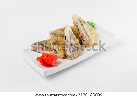 Sandwich sushi roll with breaded ham, rice and cheese. White plate on a plain background.