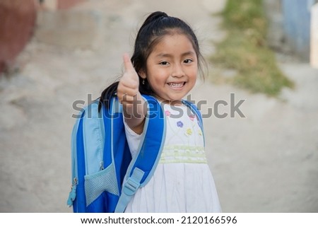 Hispanic girl ready to go to school in rural area - Latin girl on her way to school - Happy Mayan girl with thumbs up Royalty-Free Stock Photo #2120166596