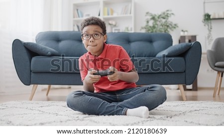 Concentrated African American boy having fun playing video game, controlling characters with joystick Royalty-Free Stock Photo #2120180639