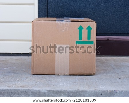 A cardboard box delivered to the house door. Sign This Way Up printed on box. Royalty-Free Stock Photo #2120181509