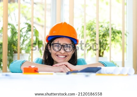 Photo of smiling female engineer wearing orange helmet.