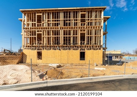 Horizontal shot of a new apartment complex under construction behind a wire fence. Royalty-Free Stock Photo #2120199104