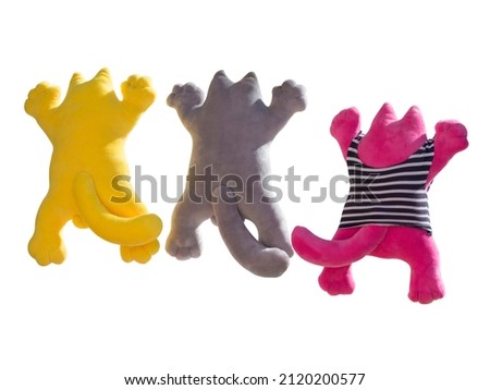 Three handmade toys in the form of cats. Isolated on white background. Sewing soft toys is a kind of needlework. Many cheerful cats - concept of friendly company. 