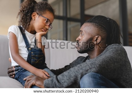 Loving african-american father dad listening to daughter`s problems with attention, supporting and calming her at home. Solving family problems. Fatherhood. Royalty-Free Stock Photo #2120200940