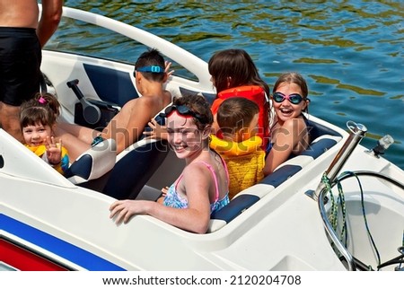 Children rest on a motor boat. Boys and girls are sitting in a speedboat. Active recreation on the water in summer. Royalty-Free Stock Photo #2120204708