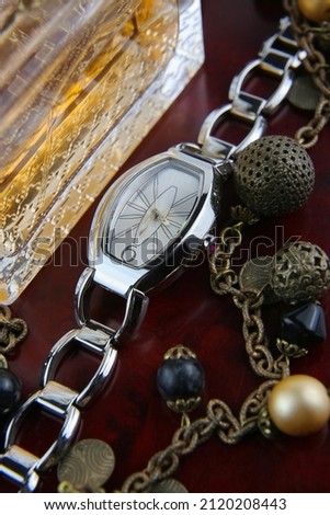 Fashionable women's wristwatches on the background of perfume and jewelry