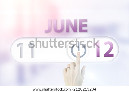 June 12nd. Day 12 of month, Calendar date.Hand finger switches pointing calendar date on sunlight office background. Summer month, day of the year concept