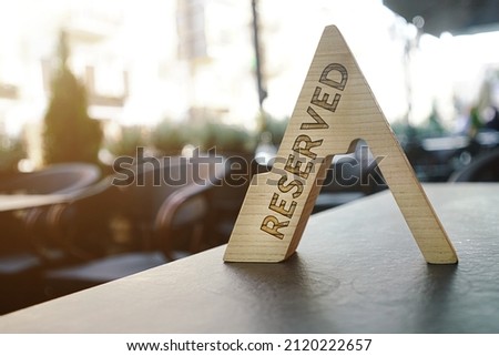 Reserved sign stands on wooden table of luxury street restaurant close view. Private party and exclusive service concept.