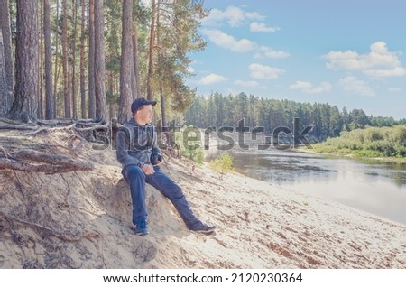 Photographer relaxes in nature near the river. Outdoor recreation.