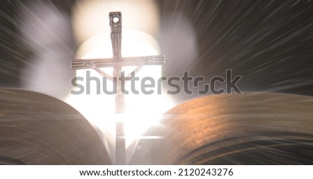 Image of christian cross with bible on glowing background. easter celebration, religion and tradition concept digitally generated image.