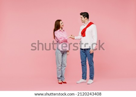 Full body young couple two friends woman man in shirt hold hands folded handshake gesture, isolated on plain pink background. Valentine's Day birthday holiday party friendship business greet concept Royalty-Free Stock Photo #2120243408