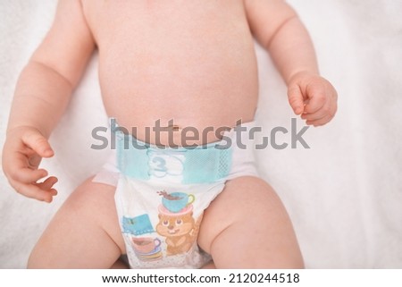 The baby's navel in the diaper. healthy stomach, a cure for gas in newborns. Intestinal colic. Daily grooming. Care about baby clean and soft body skin. Royalty-Free Stock Photo #2120244518