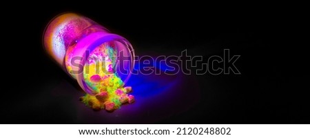 Fluorescent organic materials of red, yellow and green color for production OLED inside glass bottle in UV light. Royalty-Free Stock Photo #2120248802