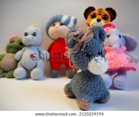 knitted toys donkey in front,turtle, tiger, boy, child, dinosaur, elephant stand on a gray background. side view. lots of soft toys