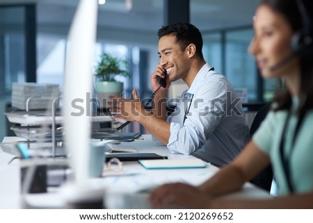 Good business is based on good communication. Shot of a young man answering the phone while working in a modern call centre. Royalty-Free Stock Photo #2120269652