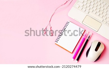 On an isolated pink background, a flat lay, a notepad for writing on a spiral, a computer mouse, headphones, pens, felt-tip pens.  Concept of online training, webinar.  Banner place for copy text.