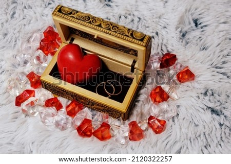 Jewelry box with a heart inside. Painted wooden box for decoration with gold rings inside. Soft fluffy background. For newlyweds, a marriage proposal. February 14, valentine. Love, decor.