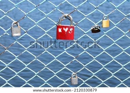 a red lock on the railing of the bridge over the river