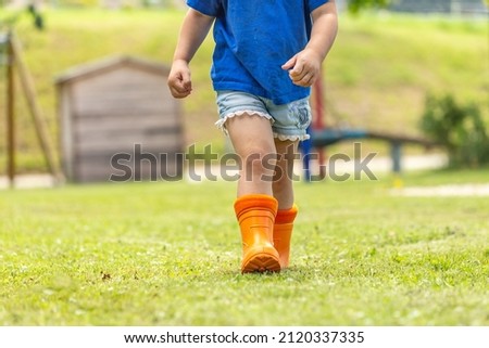 Outdoor children concept: Close-up of the legs of a child with rubber boots