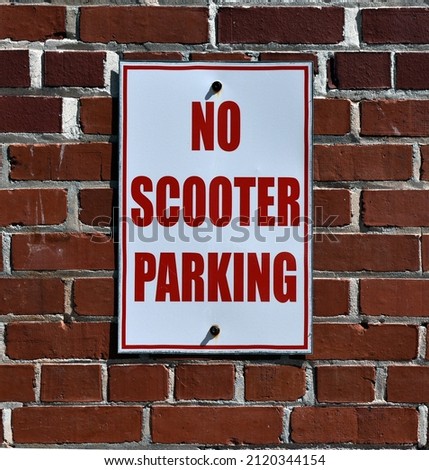 No Scooter Parking Sign on brick wall.