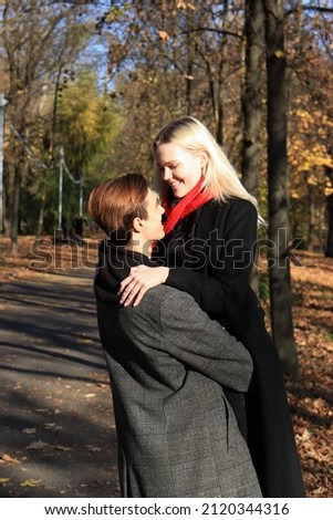 A young couple are standing in a park or forest. A couple in love - a blonde girl and guy.The guy holds the girl in his arms, they look at each other. Joint walk.Romantic relationship. Valentine's Day