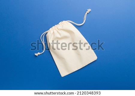Small eco sack on color background. Top view. Royalty-Free Stock Photo #2120348393
