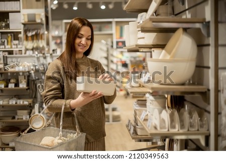 Happy housewife choosing eco friendly ceramic case with wooden lid for food storage comfortable placing in kitchen cupboard. Smiling female with box container enjoying shopping at household store