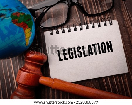 Top view earth globe,gavel and glasses with text LEGISLATION on a wooden background. Business concept.