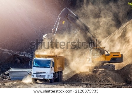 Excavator and truck for construction site. Excavation is the process of moving earth, rock or other materials with tools, equipment or explosives. It includes earthwork, trenching, wall and tunneling.
