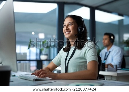 Another day, another happy client. Shot of a young woman using a headset and computer in a modern office. Royalty-Free Stock Photo #2120377424
