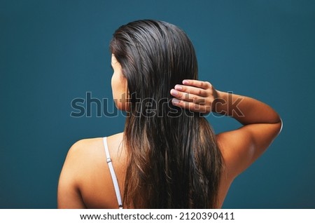 My scars-my best attire. Stunning, my dress of hellfire. Rearview studio shot of a beautiful young woman posing against a blue background. Royalty-Free Stock Photo #2120390411