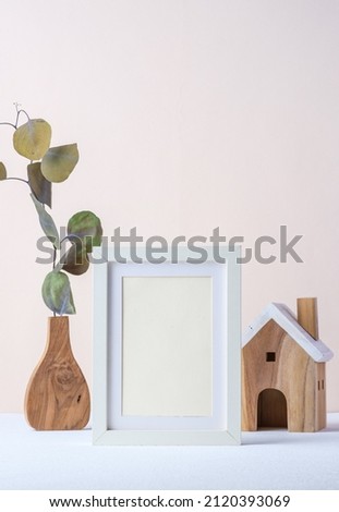 photo frame with eucalyptus branch in wood vase and wood toy on pastel background
