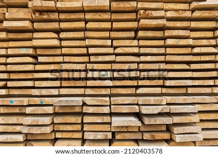 Stacked lumber filling background, wood texture. Stack of new wooden rods in the lumber warehouse. Royalty-Free Stock Photo #2120403578