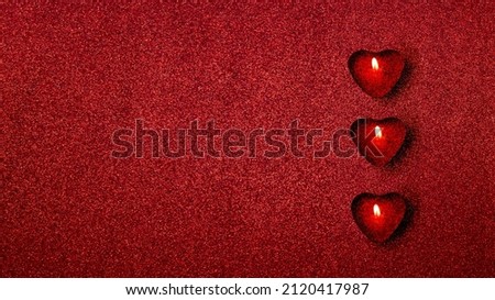 Banner flat lay candles in shape of hearts on bright glitter red background. Love concept.