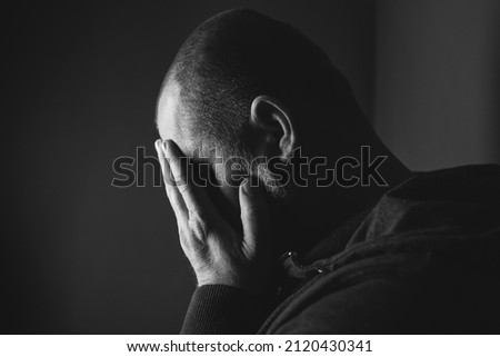 Sad man sitting in dark room. Depression and anxiety concept Royalty-Free Stock Photo #2120430341