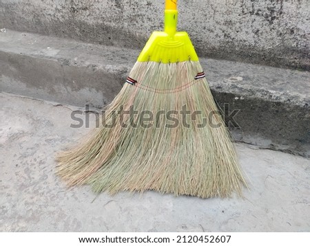 straw broom on the floor. Cleaning concept. broom tool use for cleaning. Yellow plastic broom for sweeping floors.