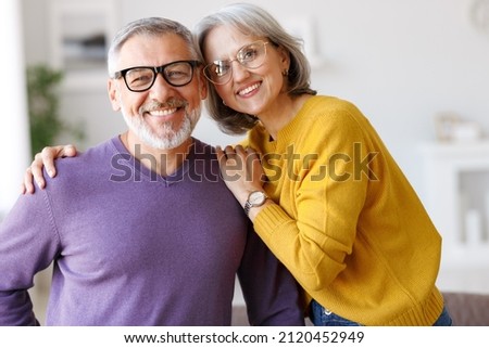 Portrait of happy beautiful senior caucasian family couple in love smiling at camera, retired man and woman hugging embracing while relaxing on sofa in living room at home, enjoying life on retirement Royalty-Free Stock Photo #2120452949