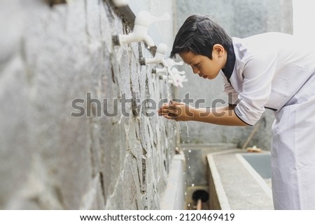 A boy performs ablution before praying at the mosque Royalty-Free Stock Photo #2120469419
