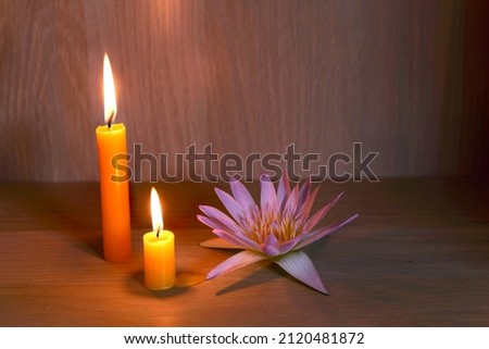 Burning candles and beautiful waterlily on a wooden floor.