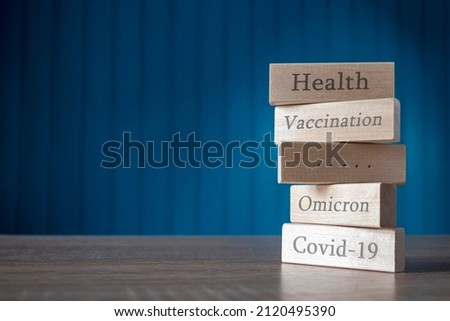 Covid-19, Omicron, vaccination, health are written in embossed wooden rectangles . The concept-vaccination will keep Health from different strains of the virus.