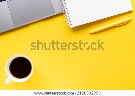 Flat lay, top view office table desk. Workspace with notebook, office supplies, pen, laptop, coffee cup with copy space on yellow background.