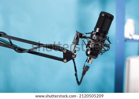 Closeup of professional microphone swivel boom arm stand in empty vlog broadcasting studio used for recording social media content. Detail of audio live broadcast digital mic.