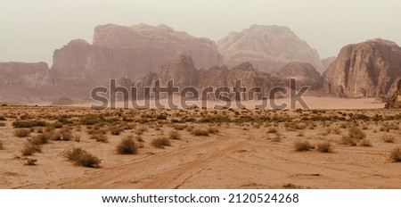 Wadi Rum desert, Jordan, The Valley of the Moon. Orange sand, haze, clouds. Designation as a UNESCO World Heritage Site. National park outdoors landscape. Offroad adventures travel background.
 Royalty-Free Stock Photo #2120524268