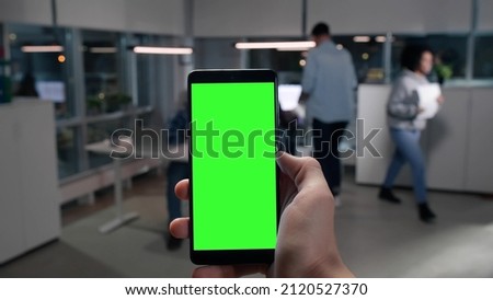 POV shot of entrepreneur use mobile phone with green screen copy space in office. Close-up of businessman holding cellphone at work. 